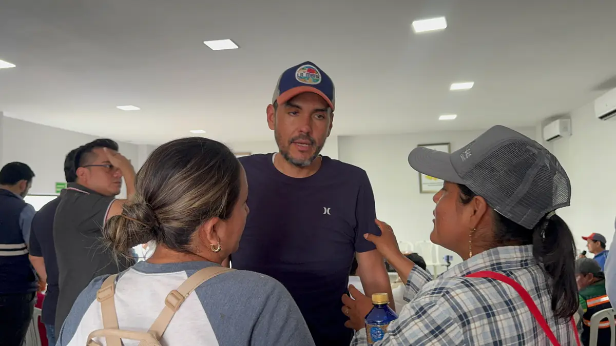 Hipólito Carrera escucha a dos mujeres durante un encuentro ciudadano